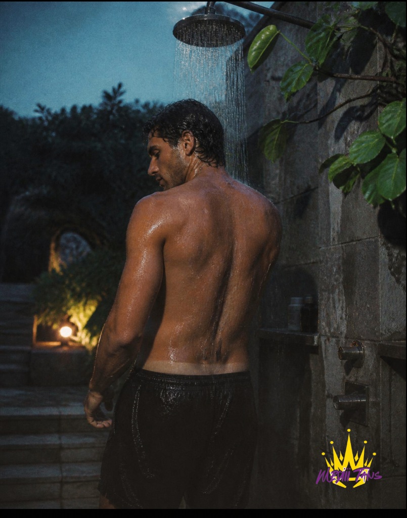 A man rinsing under an outdoor shower at dusk, water running over bronzed skin