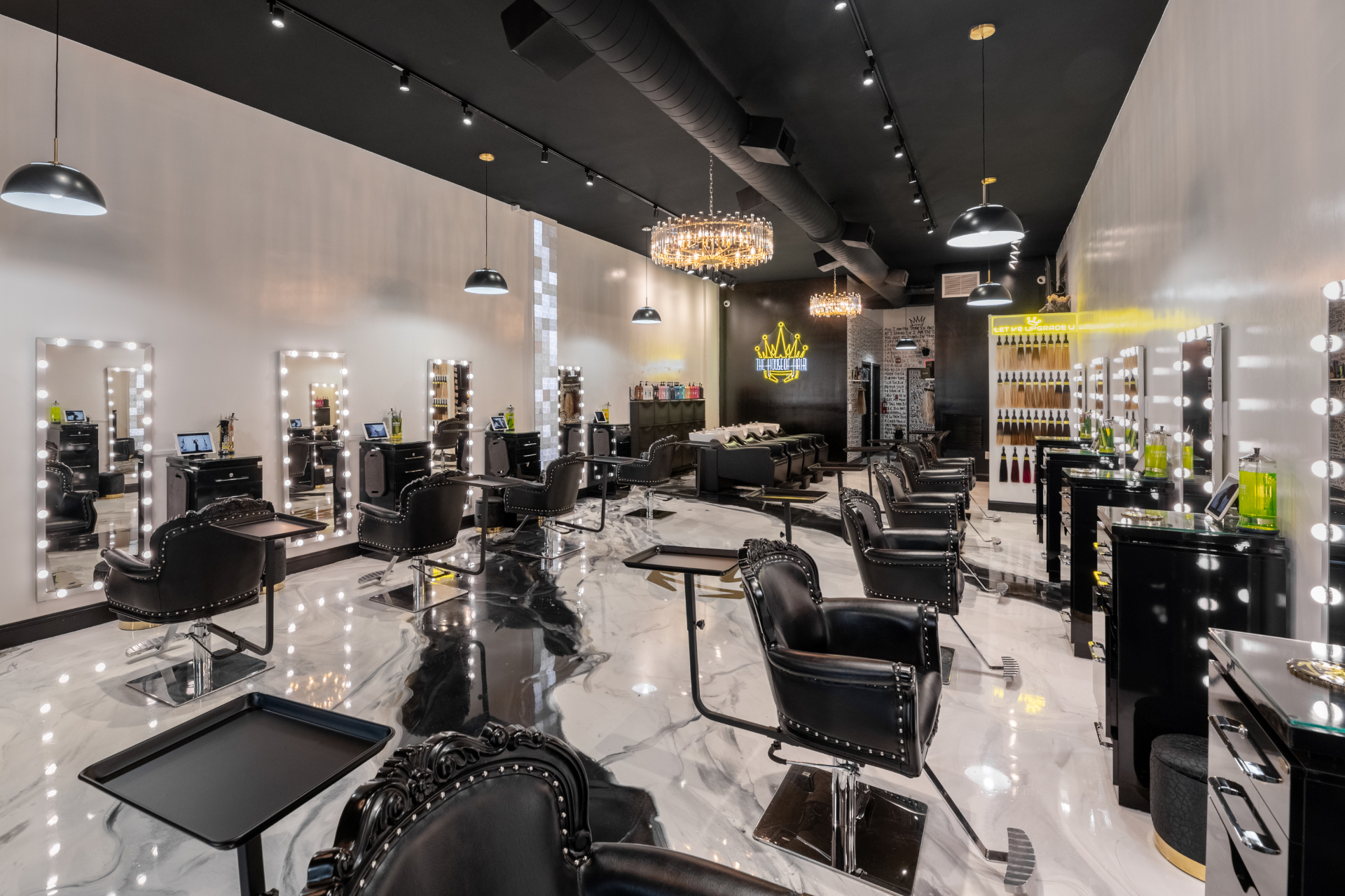 The House of Hair salon interior in Shrewsbury, New Jersey — black and gold styling stations, crystal chandeliers and marble floor